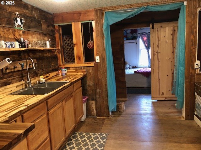 bar with dark hardwood / wood-style flooring, sink, and butcher block countertops