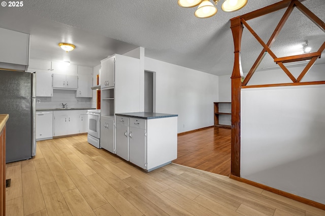 904 SE 223rd Ave, Gresham, OR 97030 - kitchen with white appliances, light wood-type flooring, dark countertops, white cabinetry, and a textured ceiling
