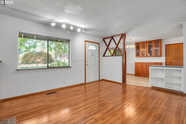 904 SE 223rd Ave, Gresham, OR 97030 - unfurnished living room with a chandelier, light wood-type flooring, a textured ceiling, and rail lighting