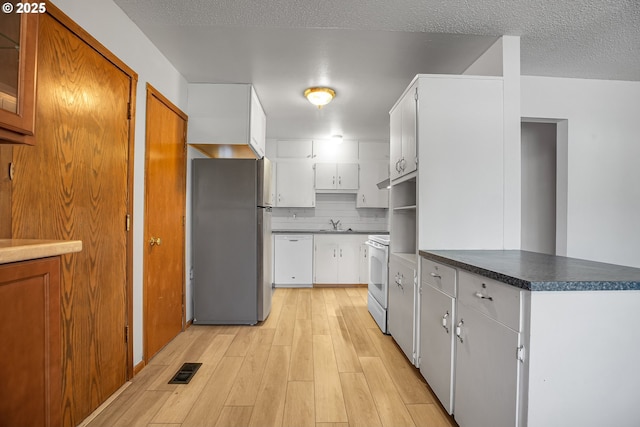 904 SE 223rd Ave, Gresham, OR 97030 - kitchen featuring white appliances, light wood-style floors, white cabinets, dark countertops, and a peninsula