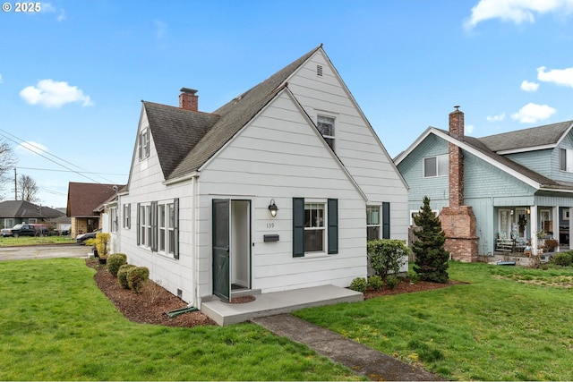 view of front of property featuring a front yard, a chimney, and a shingled roof