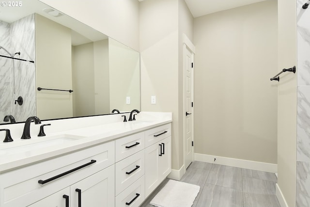 full bathroom with a sink, baseboards, and double vanity