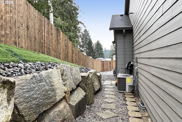 view of property exterior featuring central AC unit and fence