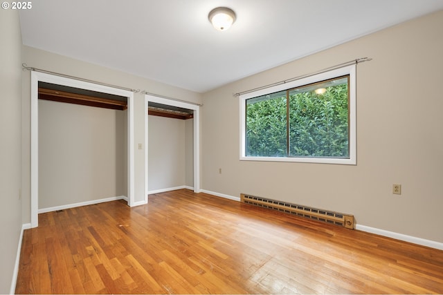 1806 8th St, Tillamook, OR 97141 - unfurnished bedroom featuring two closets, baseboards, a baseboard heating unit, and light wood finished floors