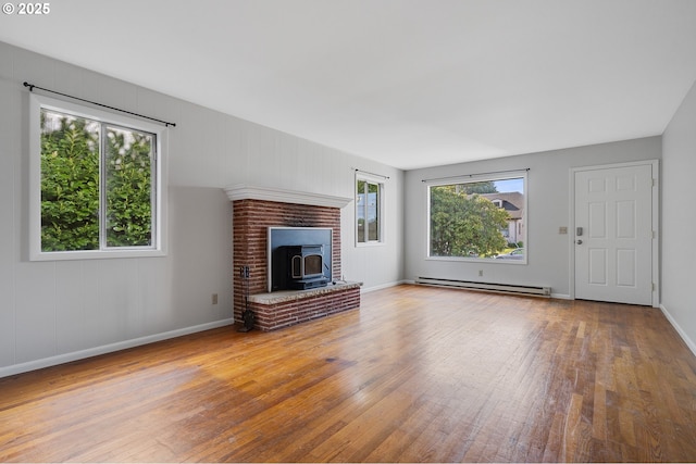 1806 8th St, Tillamook, OR 97141 - unfurnished living room featuring baseboards, a wood stove, baseboard heating, and hardwood / wood-style floors