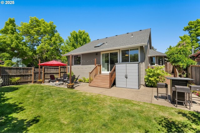 rear view of house with entry steps, a patio, an outdoor fire pit, and a shingled roof