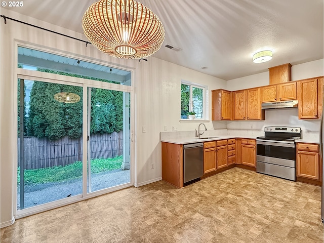 21069 SW Madeira Ter, Sherwood, OR 97140 - kitchen with appliances with stainless steel finishes, under cabinet range hood, a chandelier, light countertops, and brown cabinetry