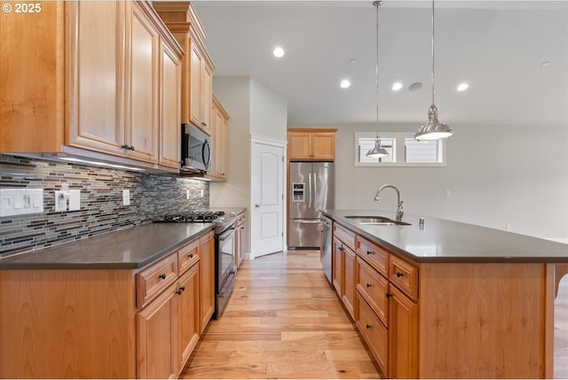 5809 NW 26th Ave, Camas, WA 98607 - kitchen with stainless steel appliances, dark countertops, light wood-style flooring, decorative backsplash, and an island with sink