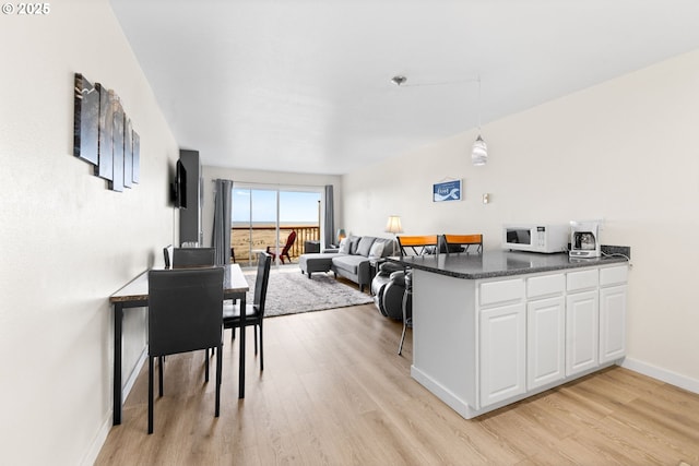 304 14th St NW Unit 304, Long Beach, WA 98631 - kitchen featuring light wood-style floors, white cabinets, dark countertops, white microwave, and a peninsula