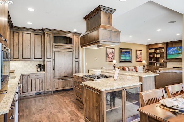 7705 NW Quinault St, Camas, WA 98607 - kitchen with custom exhaust hood, light stone countertops, built in appliances, and dark wood-style flooring