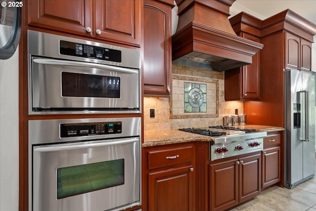 904 NE 224th Cir, Ridgefield, WA 98642 - kitchen featuring appliances with stainless steel finishes, custom exhaust hood, light stone counters, tasteful backsplash, and light tile patterned flooring