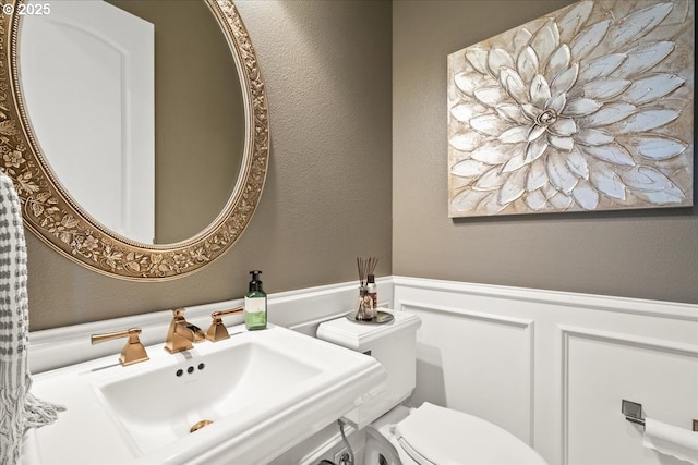904 NE 224th Cir, Ridgefield, WA 98642 - half bath featuring a sink, a textured wall, a wainscoted wall, a decorative wall, and toilet