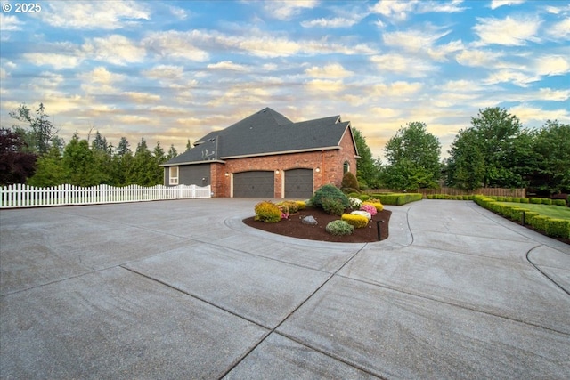 904 NE 224th Cir, Ridgefield, WA 98642 - property exterior at dusk featuring curved driveway, a garage, brick siding, and a shingled roof