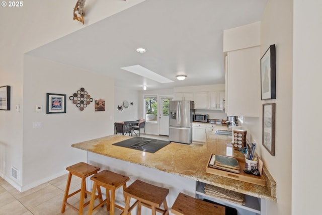 kitchen with sink, stainless steel appliances, white cabinets, a kitchen bar, and kitchen peninsula