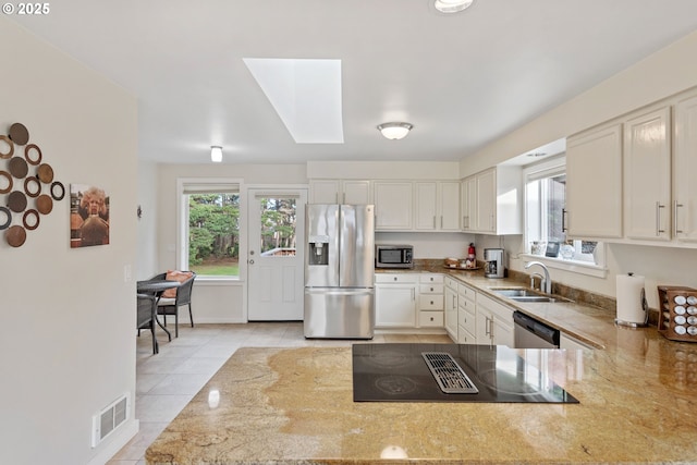 kitchen with a healthy amount of sunlight, appliances with stainless steel finishes, sink, and white cabinets