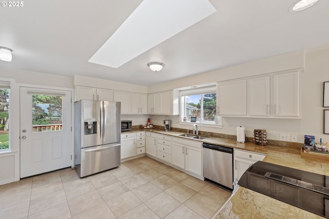 kitchen featuring stainless steel appliances, a skylight, sink, and white cabinets