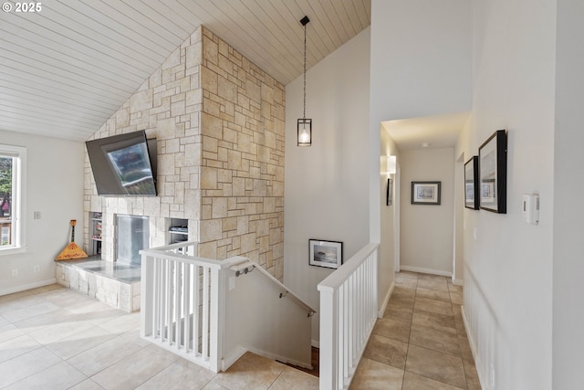 hall featuring light tile patterned floors, wood ceiling, and high vaulted ceiling