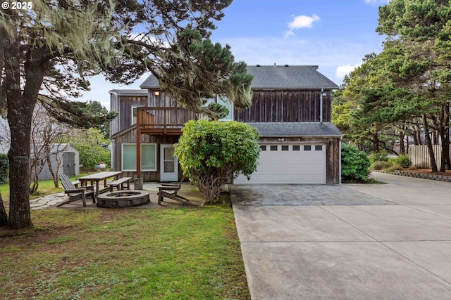 view of front of property featuring a garage, a fire pit, a front lawn, and a balcony