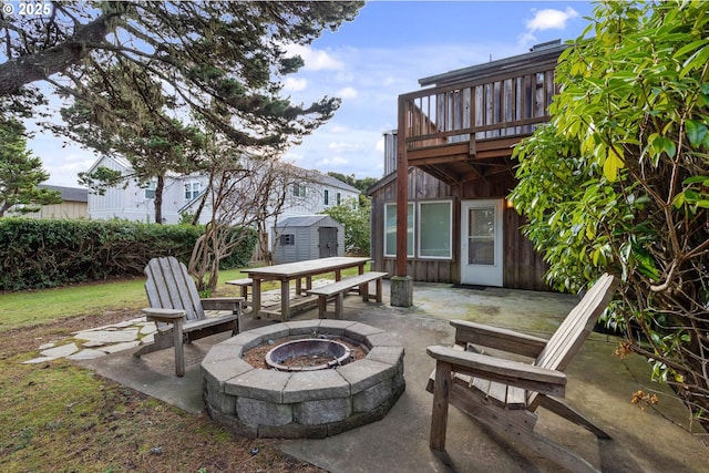 view of patio featuring a shed, a deck, and a fire pit