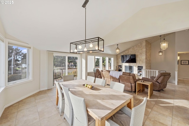 dining room featuring lofted ceiling, a fireplace, and light tile patterned floors