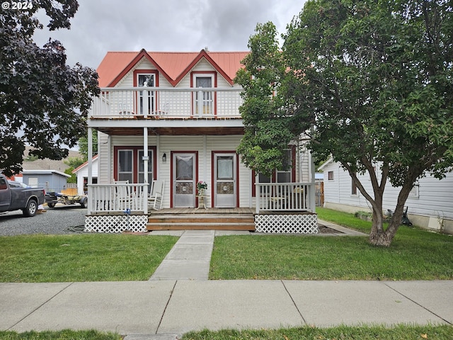 victorian home featuring a porch, a front yard, and a balcony