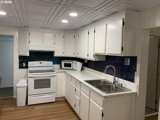 kitchen featuring white appliances, backsplash, a sink, and under cabinet range hood