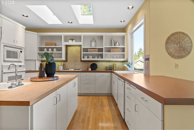 kitchen featuring white cabinets, sink, white appliances, and decorative backsplash