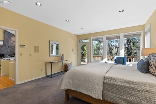 bedroom featuring carpet flooring, access to outside, and a stone fireplace