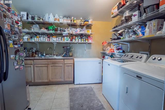 laundry area with cabinets, washing machine and dryer, indoor wet bar, and light tile patterned floors