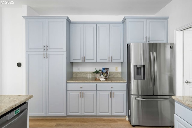 kitchen featuring light wood finished floors, light stone counters, and stainless steel appliances