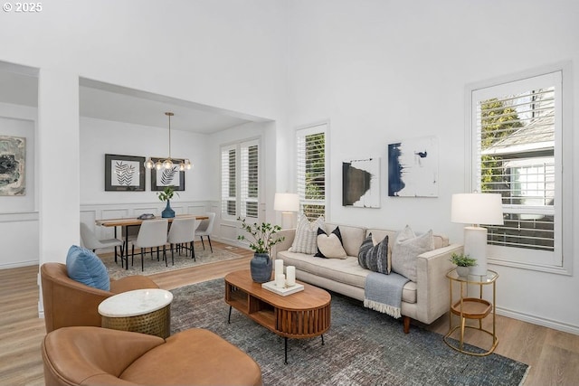 living area featuring a wealth of natural light, wainscoting, a notable chandelier, and wood finished floors