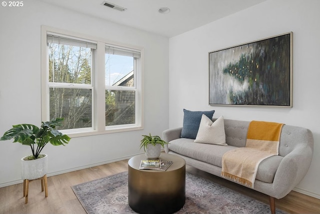 living area with baseboards, visible vents, and wood finished floors