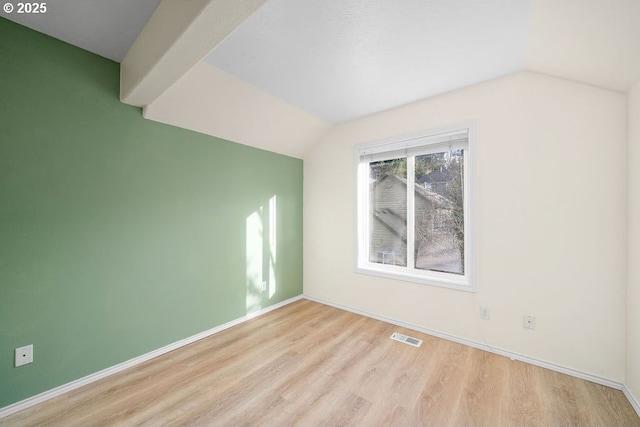 spare room featuring lofted ceiling, baseboards, visible vents, and wood finished floors