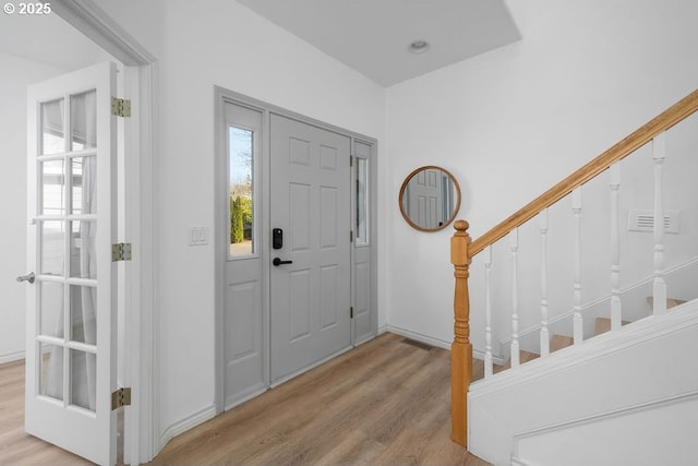 entryway with a healthy amount of sunlight, stairs, visible vents, and wood finished floors