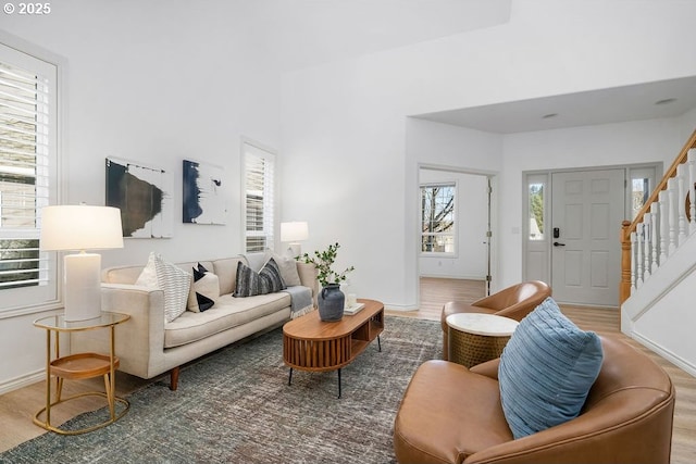 living area with stairway, wood finished floors, and baseboards