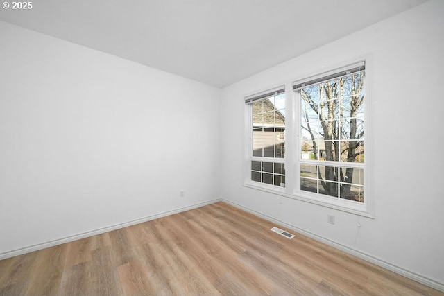 unfurnished room with wood finished floors, visible vents, and baseboards