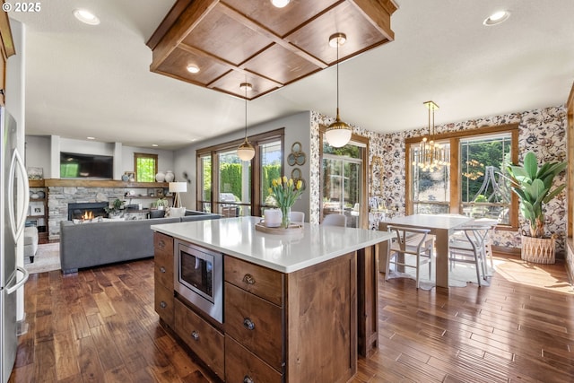 kitchen with appliances with stainless steel finishes, dark wood-style flooring, healthy amount of natural light, light countertops, and wallpapered walls