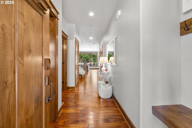 hallway with wood-type flooring, baseboards, and recessed lighting
