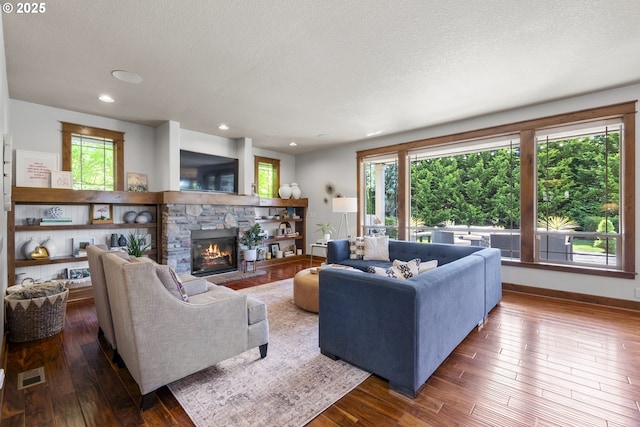 living area featuring a textured ceiling, hardwood / wood-style flooring, plenty of natural light, a fireplace, and baseboards