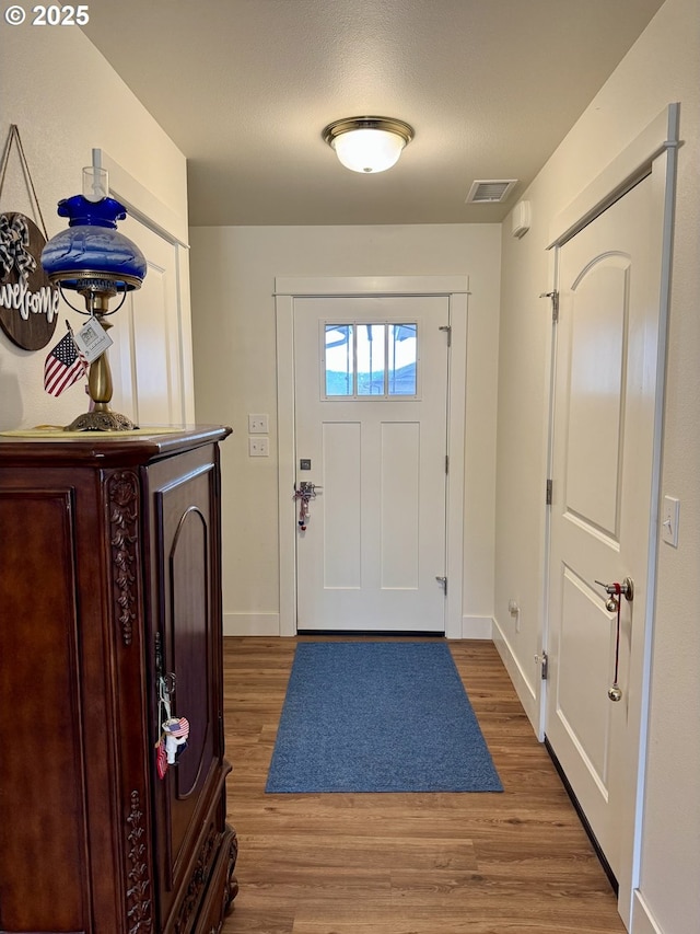 entryway with wood finished floors, visible vents, and baseboards