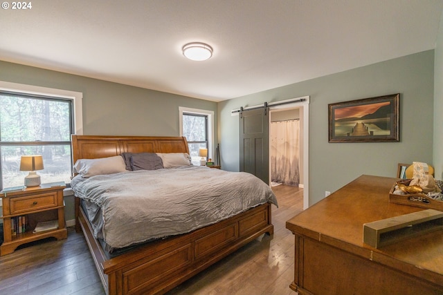 bedroom featuring a barn door and hardwood / wood-style flooring