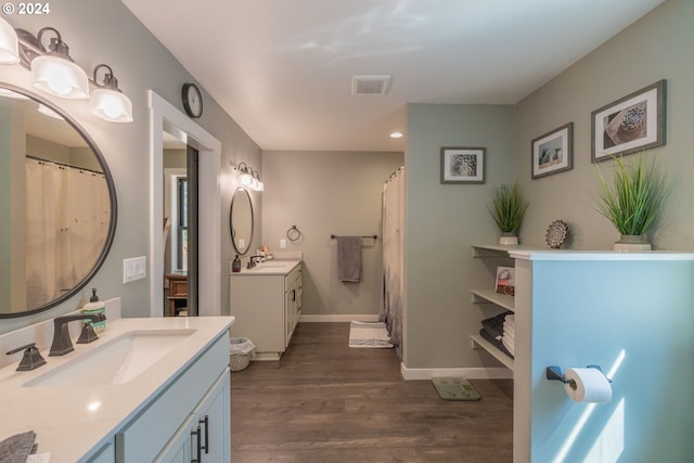 full bath featuring wood finished floors, two vanities, a sink, and visible vents