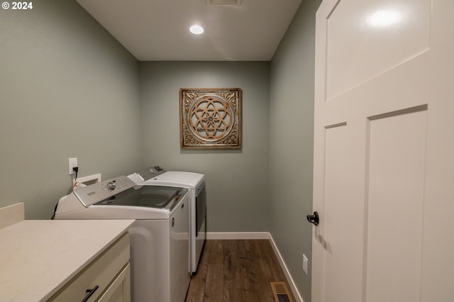 clothes washing area with washing machine and dryer, visible vents, baseboards, cabinet space, and dark wood-style floors