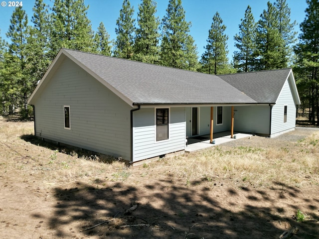 view of front of home with a patio, a shingled roof, and crawl space