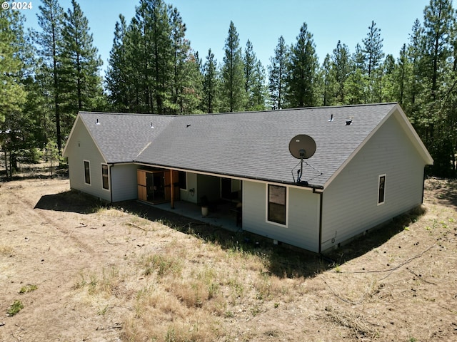 rear view of property featuring a patio area and roof with shingles