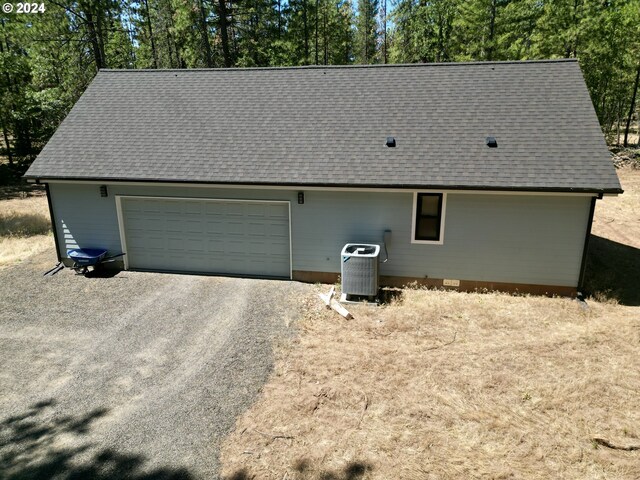 exterior space with central AC unit, crawl space, gravel driveway, and a shingled roof