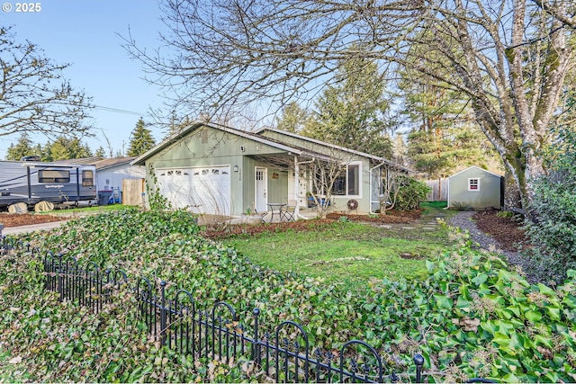 view of front facade featuring a storage unit, an attached garage, and fence