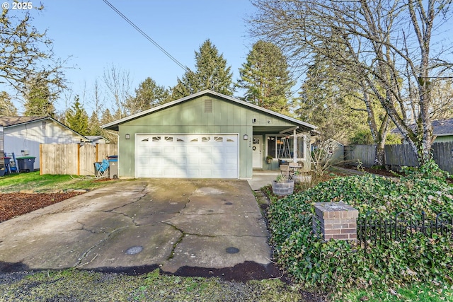 view of front of home featuring driveway, a garage, and fence