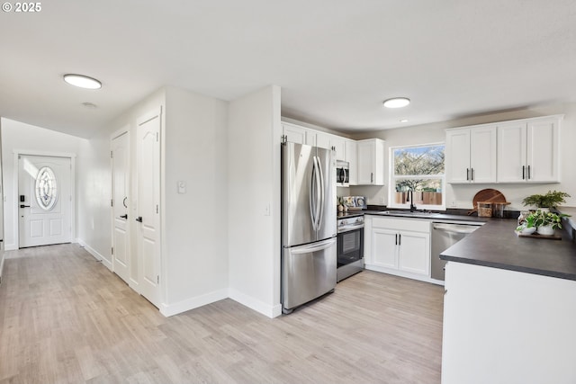 210 Mill St, Dayton, OR 97114 - kitchen featuring stainless steel appliances, dark countertops, light wood-type flooring, and white cabinets