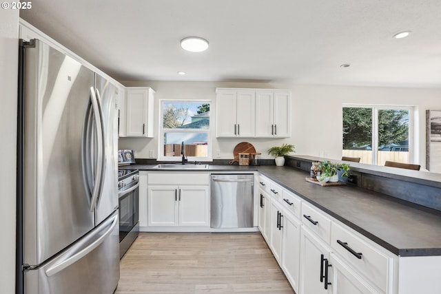 210 Mill St, Dayton, OR 97114 - kitchen featuring appliances with stainless steel finishes, a peninsula, dark countertops, light wood finished floors, and recessed lighting